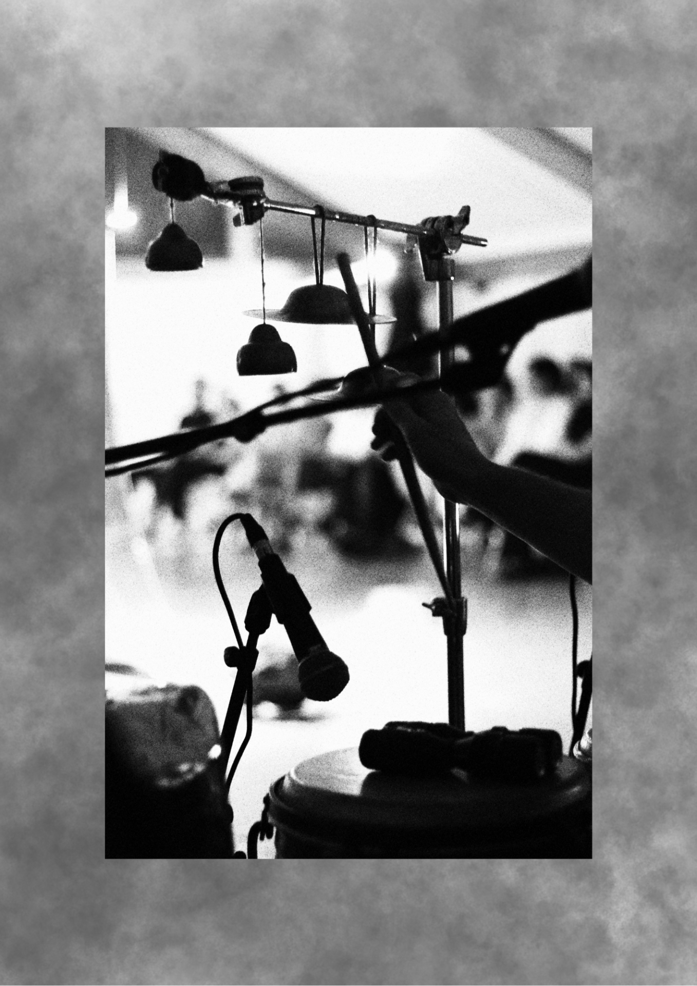 Percussion setup with suspended bells in grainy black and white.