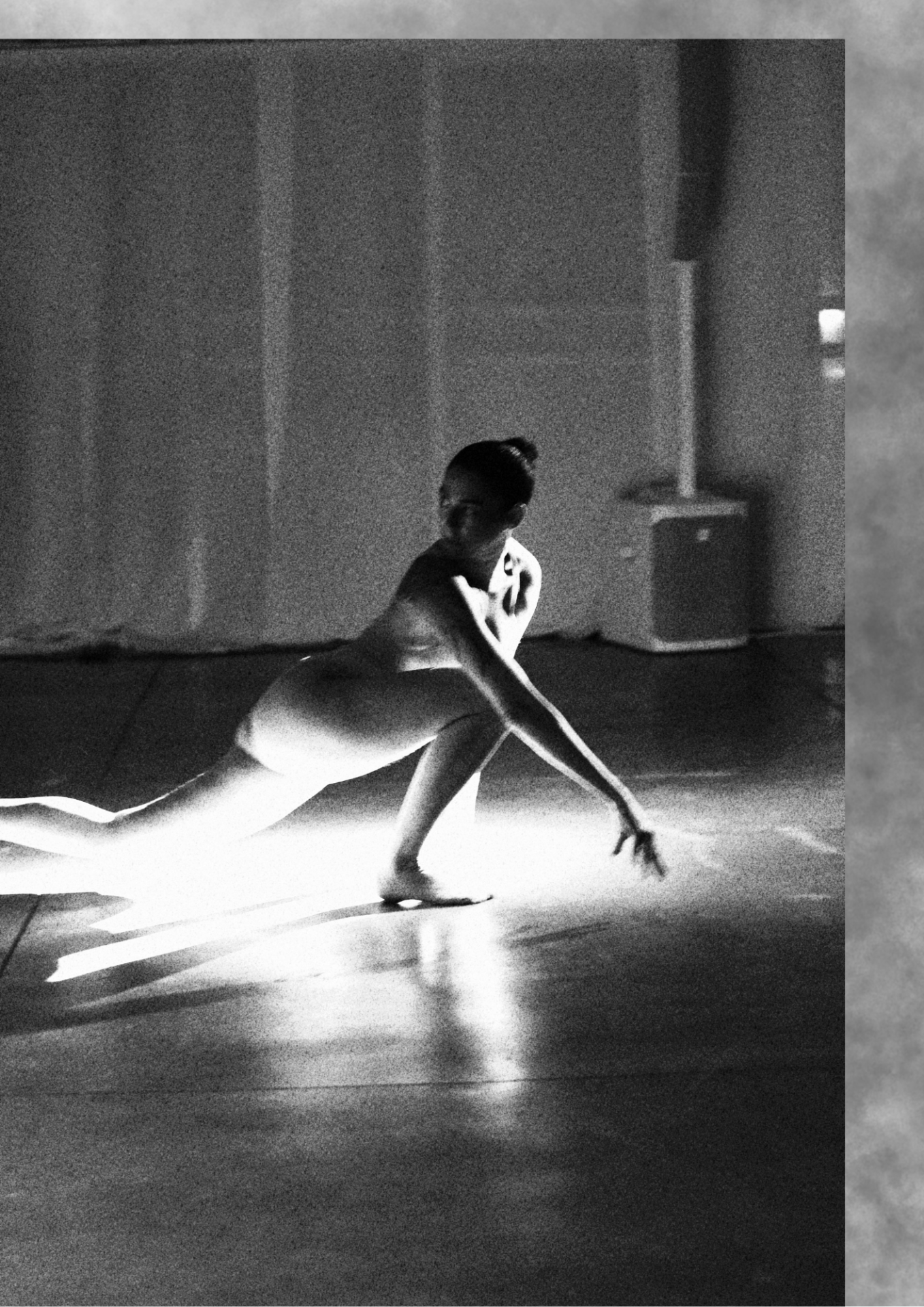 Dancer moving low across a lit floor in black and white.